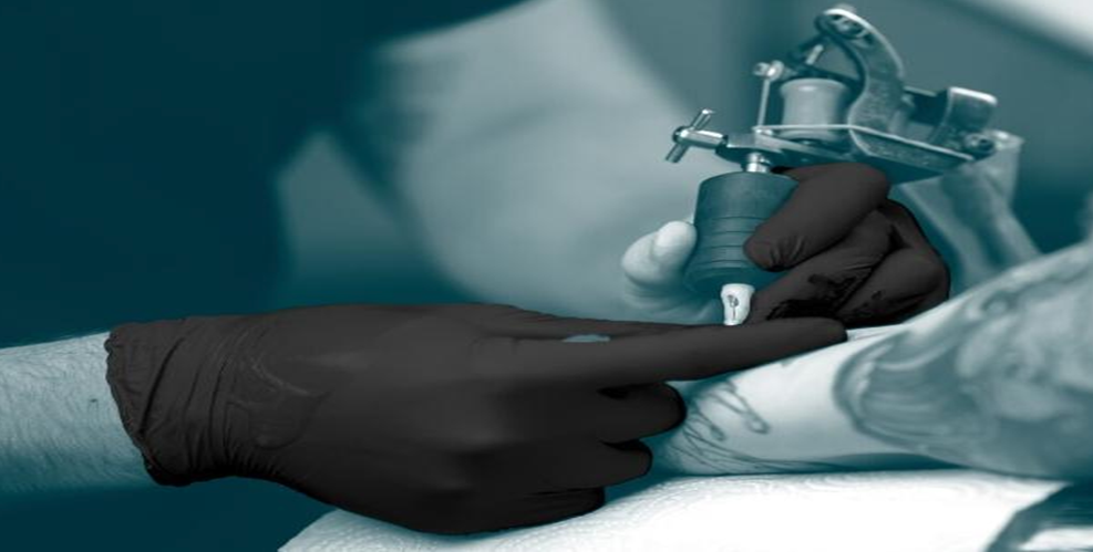 Artist applying a tatto stencil with black nitrile gloves